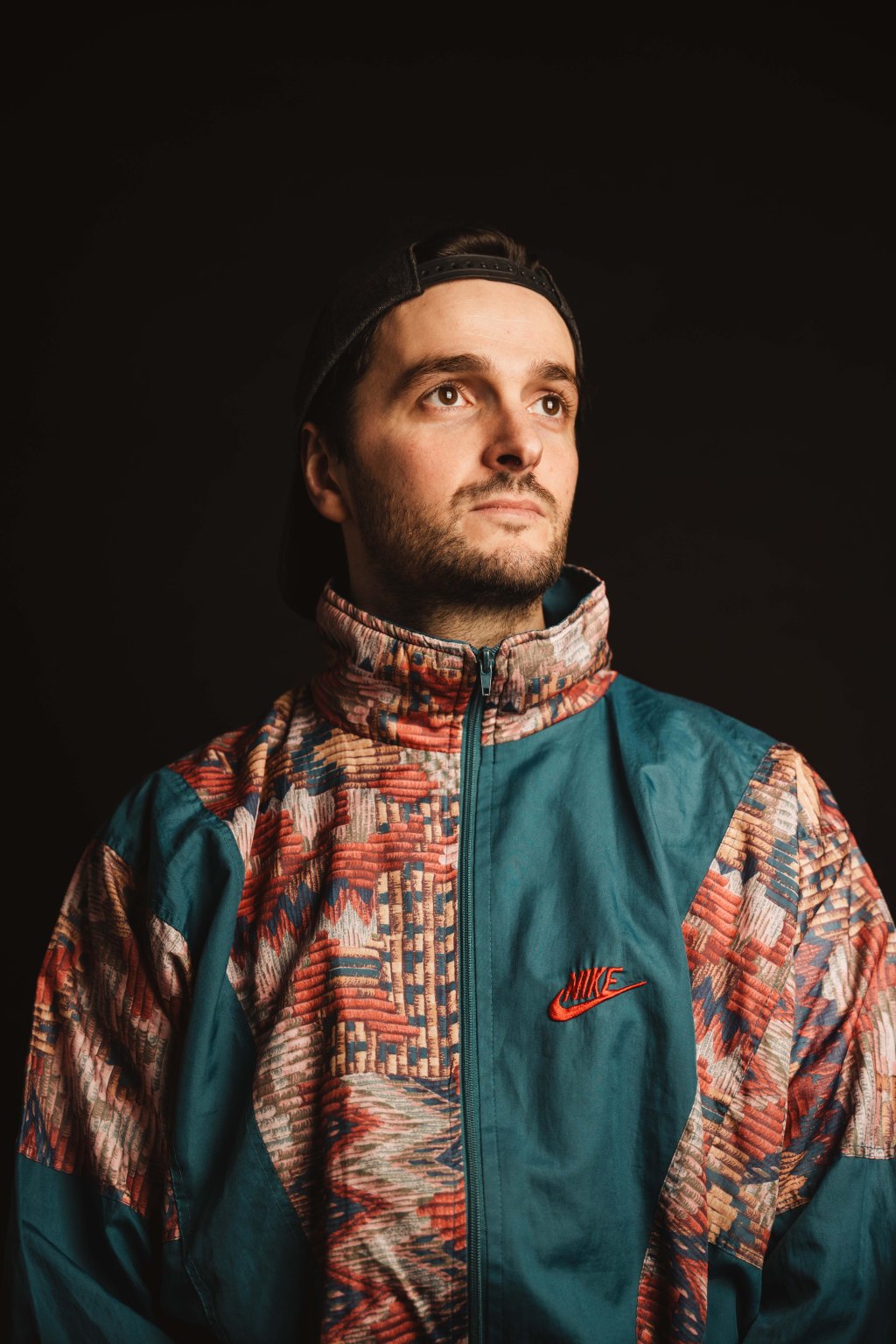 Portrait de VAPA vêtu d'une veste multicolore à col haut.